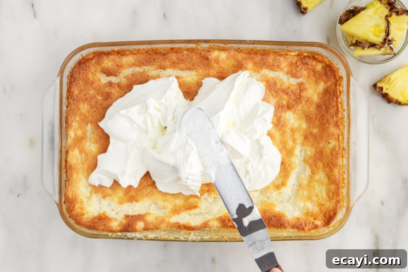 Tropical Pineapple Angel Delight 10 icing spatula spreading whipped cream onto pineapple angel food cake