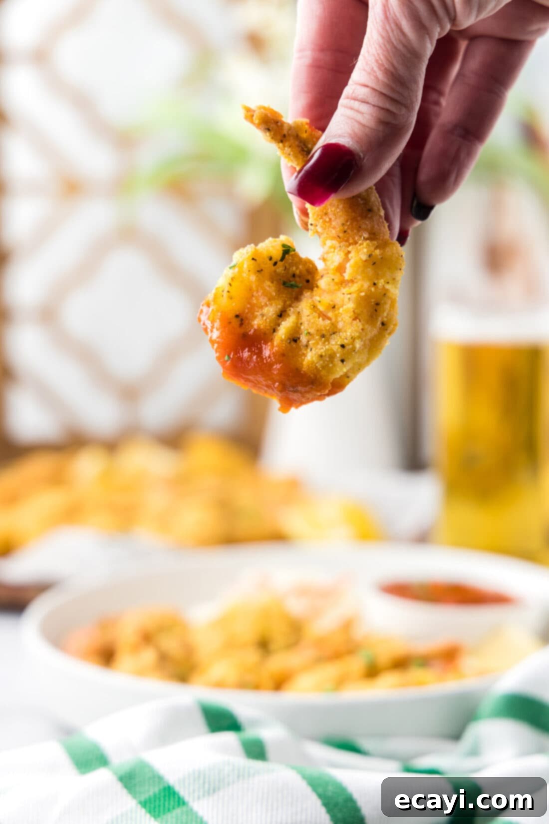 Golden Crispy Shrimp 2 A hand holding a Fried Shrimp dipped in cocktail sauce