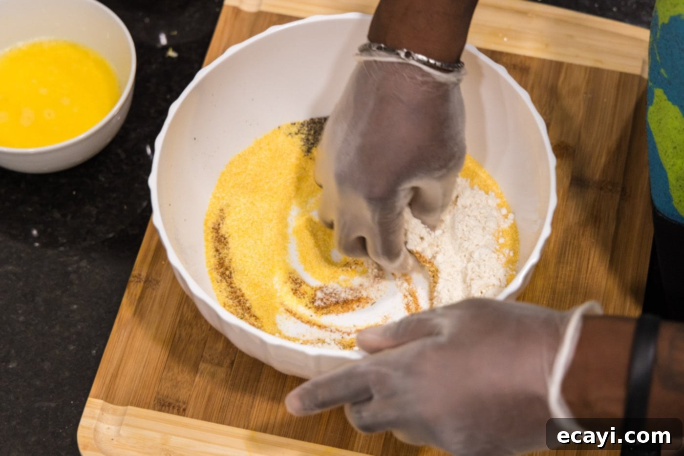 Golden Crispy Shrimp 7 hand mixing spices, seasonings, and flour in a bowl with cornmeal