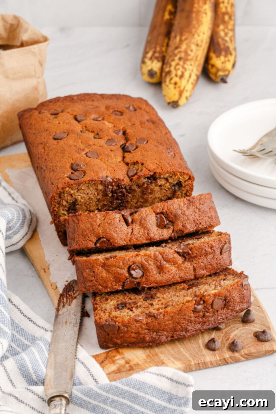 Banana Chip Indulgence 16 A delicious loaf of chocolate chip banana bread, perfectly sliced on a rustic wooden cutting board, ready to be served.