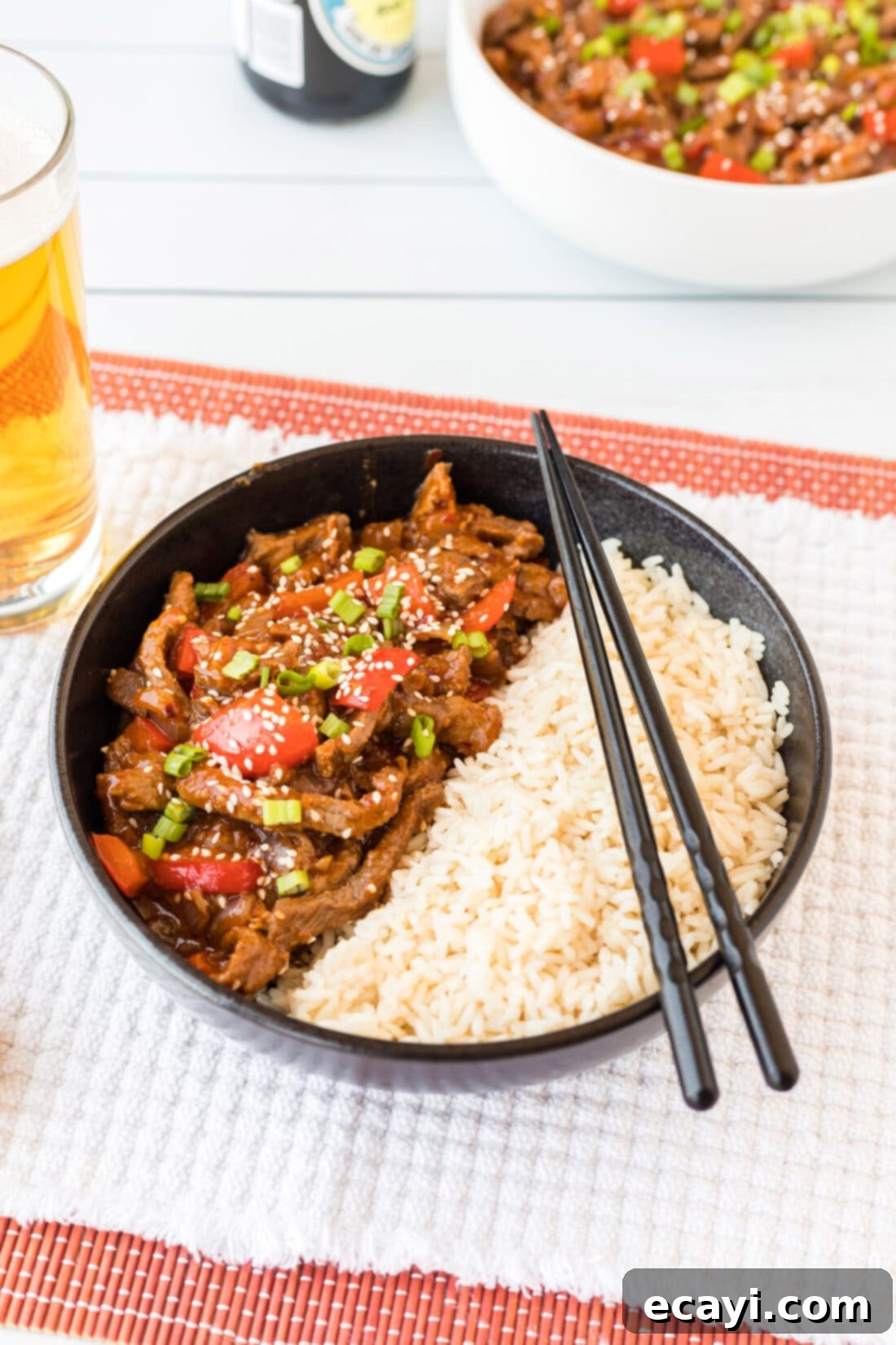 Crispy Beijing Beef 2 A bowl of vibrant Beijing Beef served with steamed white rice, garnished with green onions.