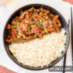Crispy Beijing Beef 13 Beijing Beef served with rice in a bowl, garnished with green onions and sesame seeds.
