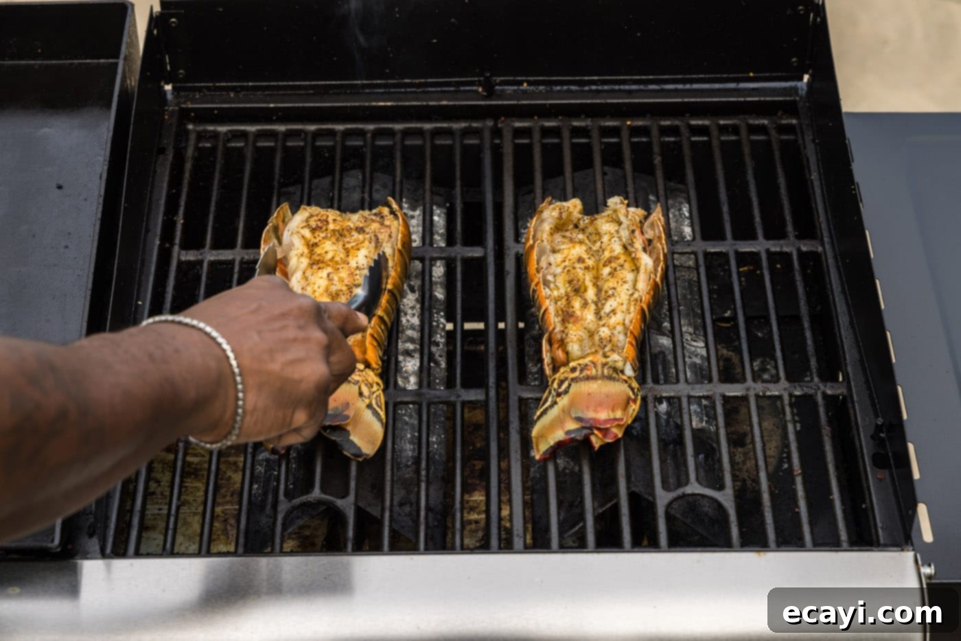 Succulent Grilled Lobster Tail 12 tongs flipping lobster tails over on the grill