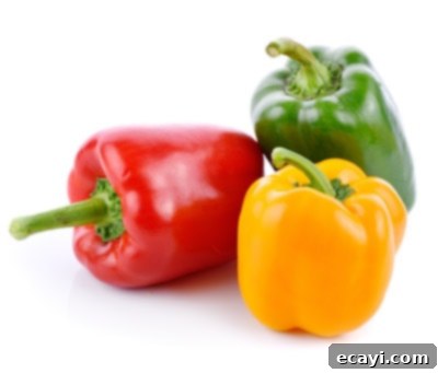Düşük Karbonhidratlı Sebzeler: Ne Yenmeli, Nelerden Kaçınmalı 13 A trio of colorful bell peppers (red, yellow, green) on a white background.