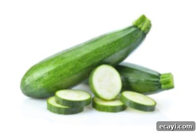 Düşük Karbonhidratlı Sebzeler: Ne Yenmeli, Nelerden Kaçınmalı 10 Fresh green zucchini and a sliced piece, ready for culinary use.