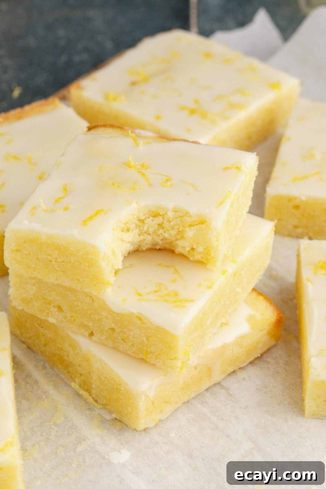 Sunshine Lemon Brownies 12 Stack of Lemon Brownies with a bite taken out of the top brownie, showcasing the texture