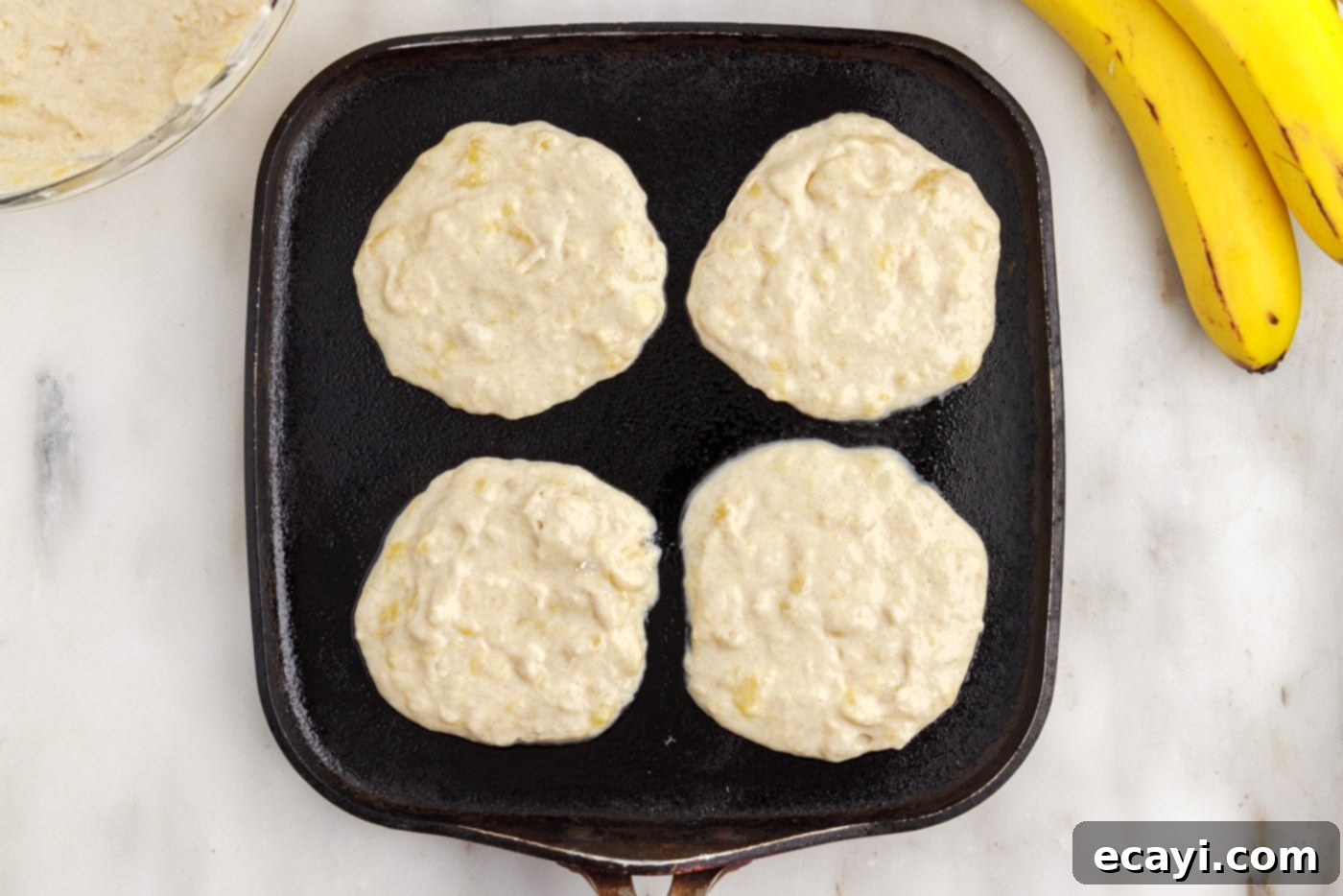 Fluffy Banana Bliss 11 Banana pancake batter poured onto a hot griddle, starting to cook