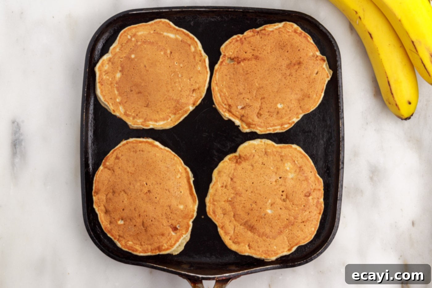 Fluffy Banana Bliss 12 Golden brown banana pancakes cooking on a griddle, ready to be flipped or already flipped