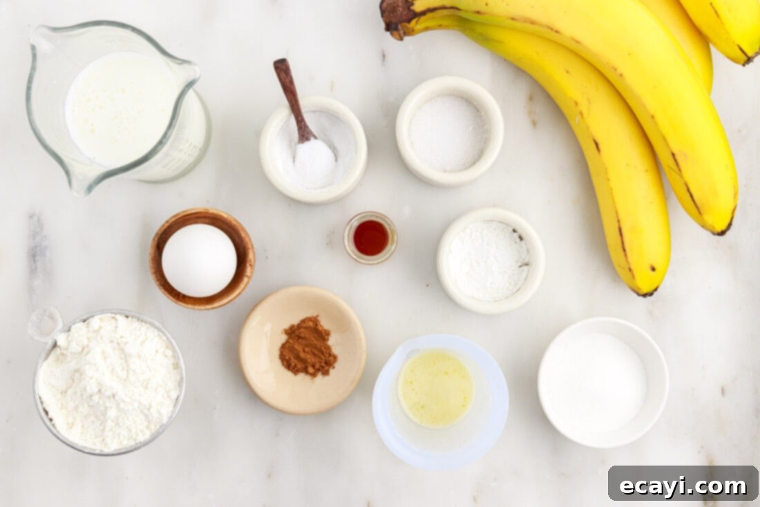 Fluffy Banana Bliss 4 Various ingredients for banana pancakes laid out on a white surface, including bananas, flour, sugar, butter, buttermilk, and spices