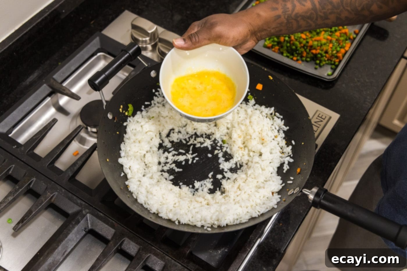 Wok-Fired Pork Fried Rice 11 Pouring whisked eggs directly into a cleared well in the center of white rice in a wok