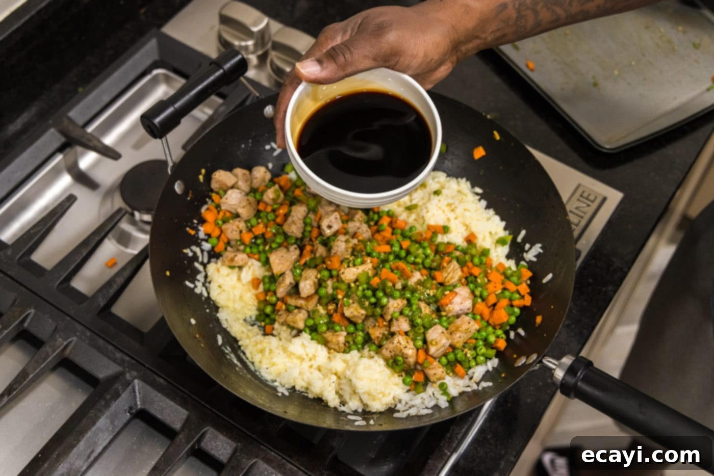 Wok-Fired Pork Fried Rice 14 Pouring a stream of soy sauce over the pork, vegetables, and rice mixture in a skillet