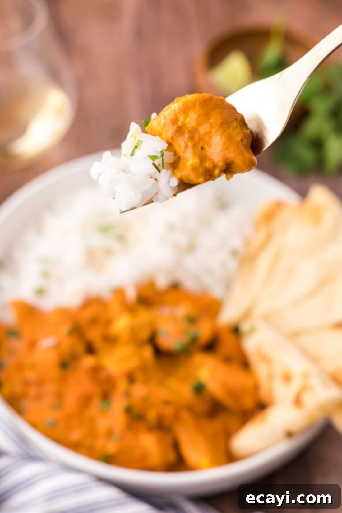 Chicken Tikka Masala 3 A close-up of a fork holding a piece of tender Chicken Tikka Masala, with fluffy white rice in the background.