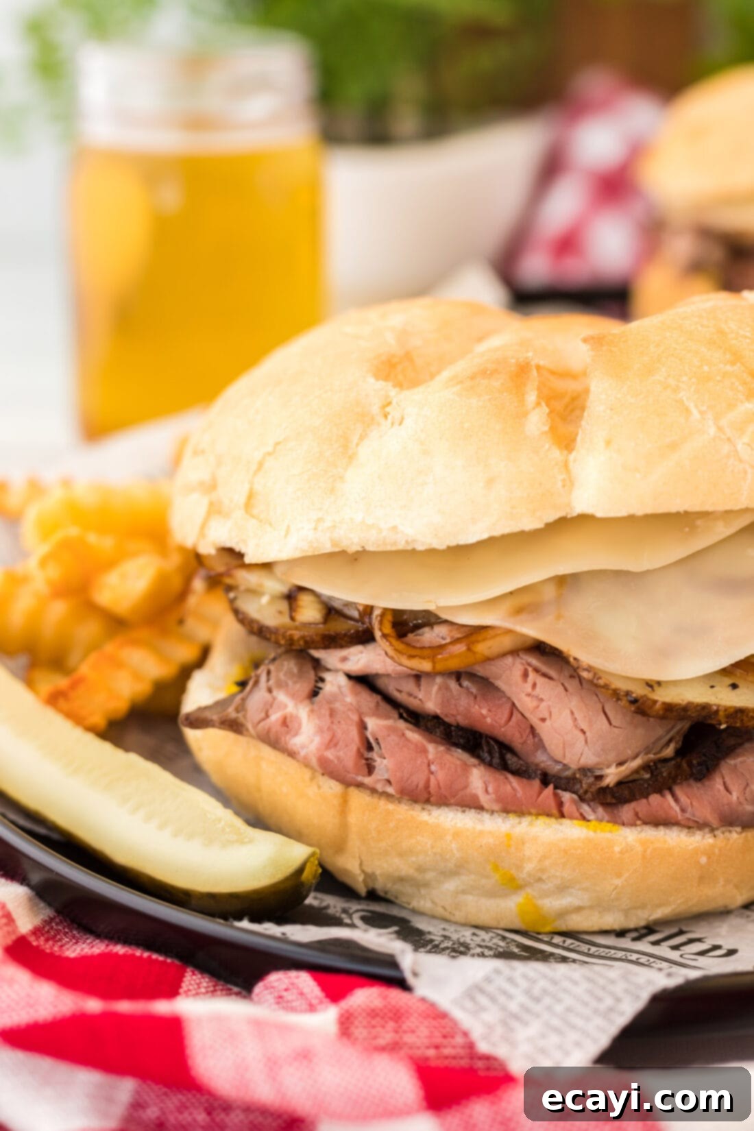 Tender Roast Beef Perfection 2 Close up of a gourmet roast beef sandwich with balsamic onions, potatoes, and provolone