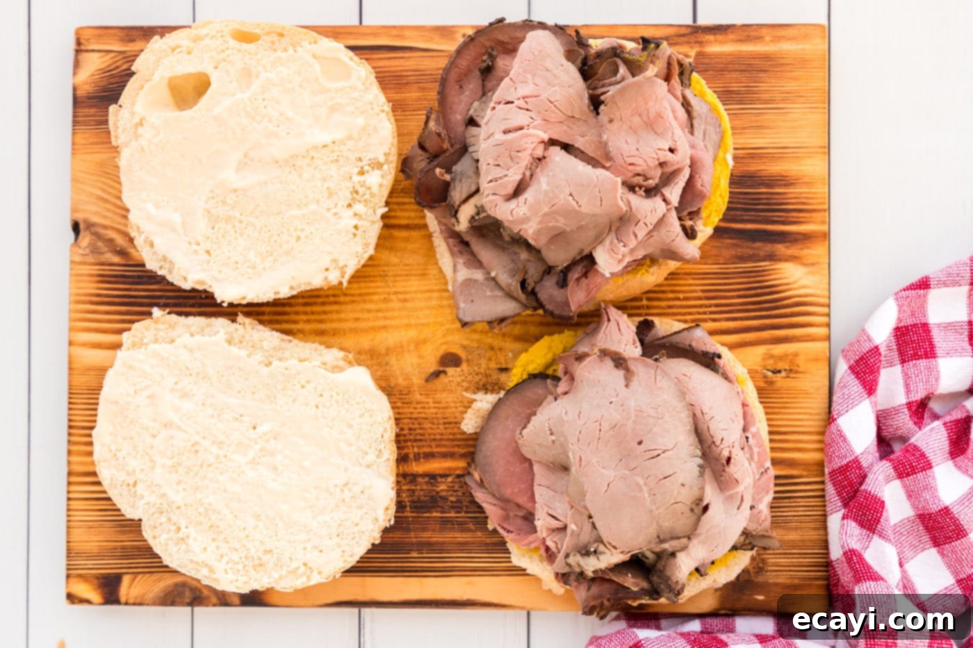 Tender Roast Beef Perfection 10 Placing thinly sliced roast beef on a bun spread with mustard