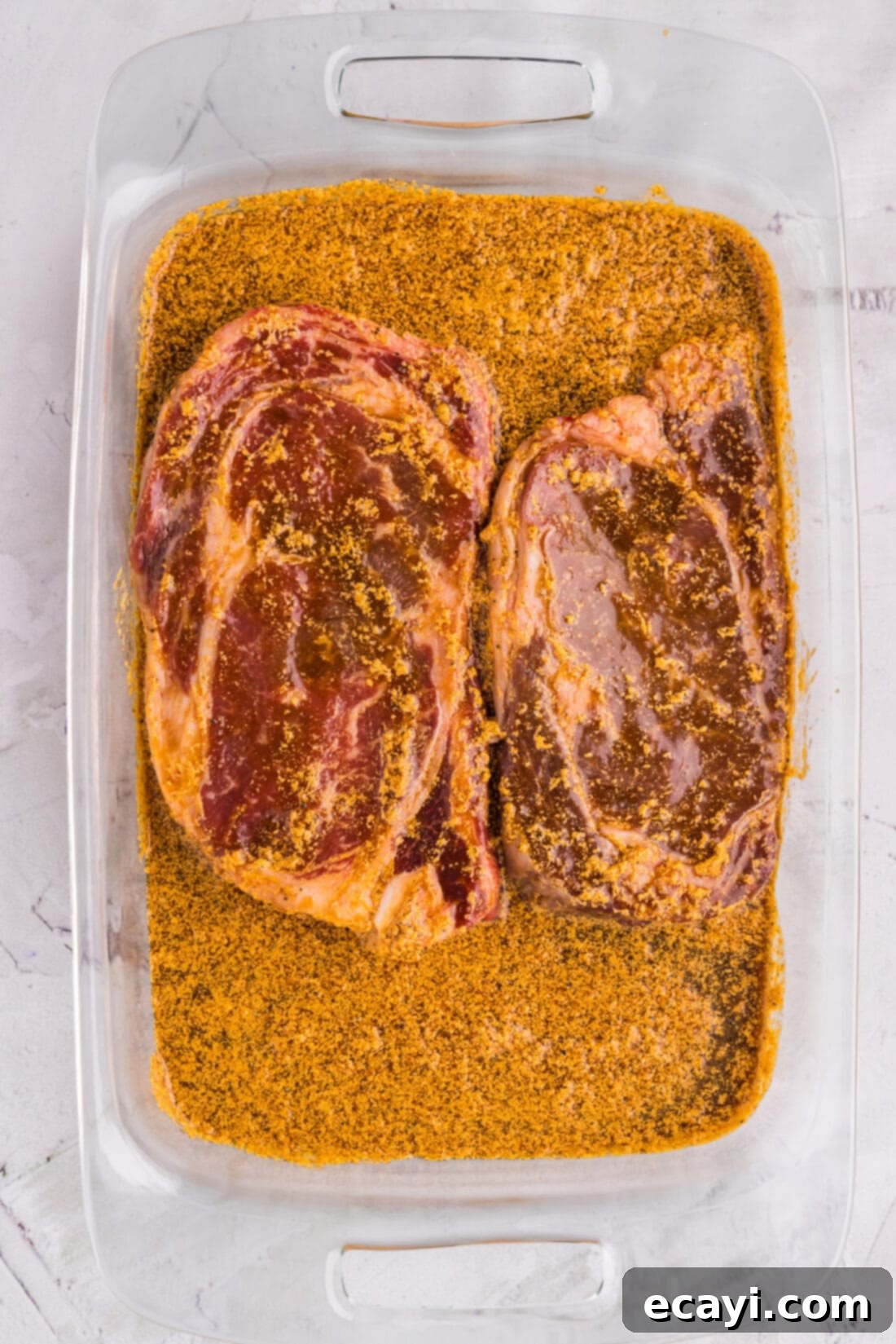 The Perfect Ribeye Marinade 2 Ribeye Steak Marinade in a glass dish with two ribeyes