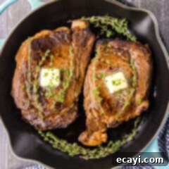 The Ultimate Cast Iron Ribeye 11 Two Cast Iron Ribeyes in a cast iron pan with butter pats on top
