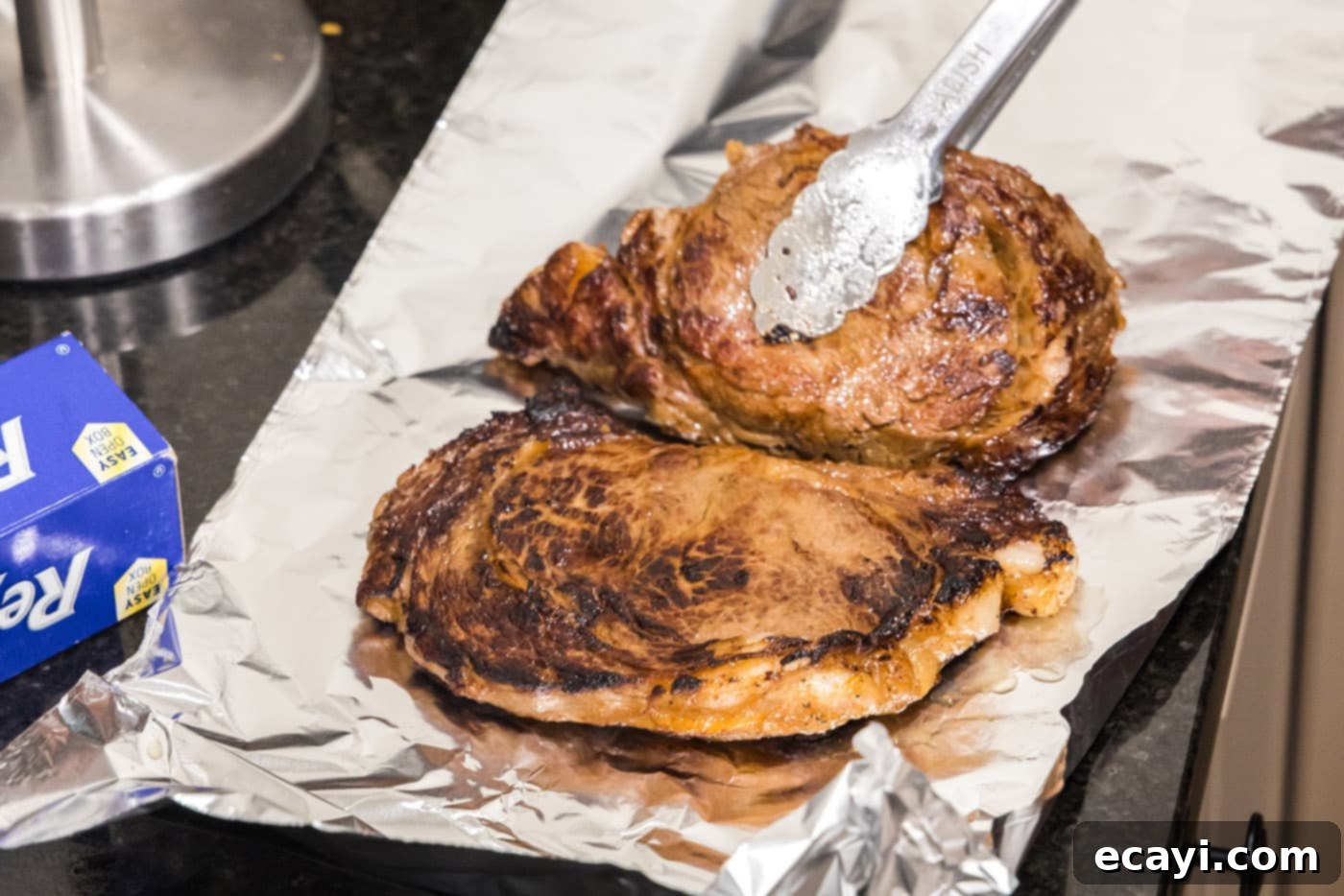 The Ultimate Cast Iron Ribeye 8 Cooked ribeye steaks resting in foil to redistribute juices