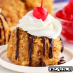 Crispy-Coated Cream Dream 17 Close up of Fried Ice Cream on a plate with chocolate sauce, whipped cream and a cherry on top.