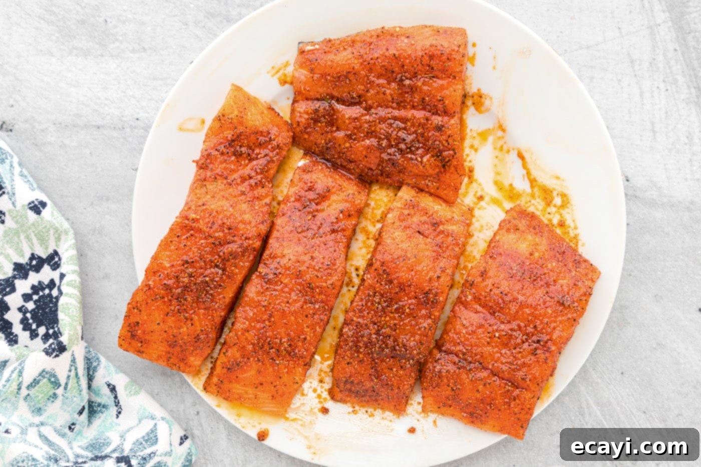 Easy Crispy Air Fryer Salmon 6 Salmon filets generously coated in seasonings on a plate, ready for the air fryer