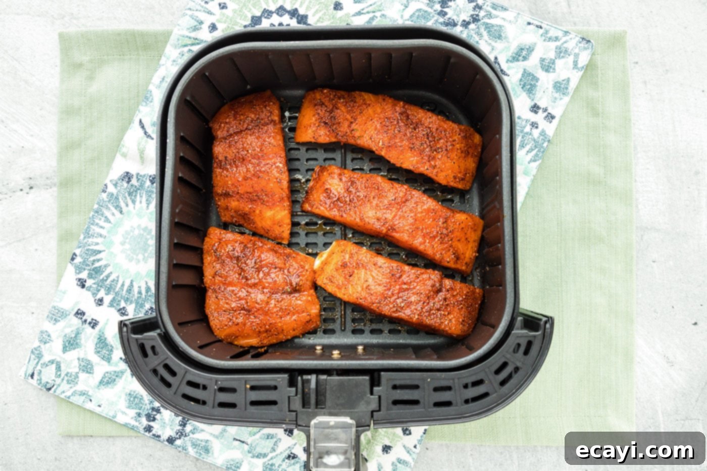 Easy Crispy Air Fryer Salmon 7 Salmon filets arranged in an air fryer basket, skin side down