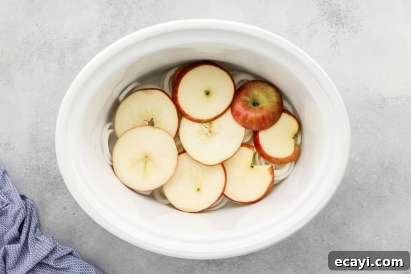 Fall-Off-The-Bone Slow Cooker BBQ Country Ribs 5 apple slices over onion slices in a crock