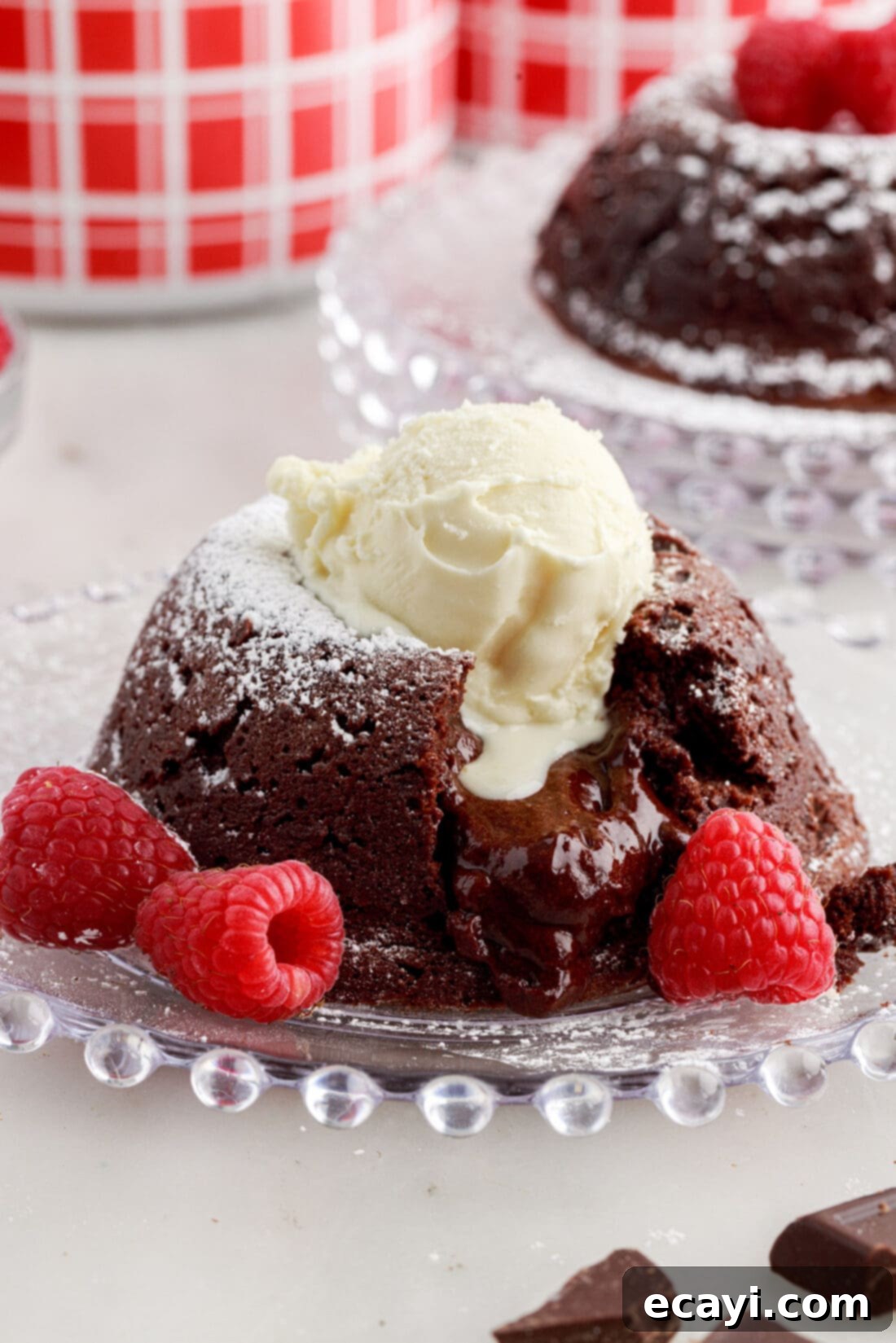 Molten Chocolate Bliss 2 Lava Cake on a plate with raspberries topped with powdered sugar and a scoop of ice cream