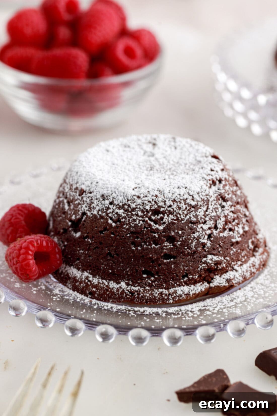 Molten Chocolate Bliss 19 Lava Cake on a plate with raspberries topped with powdered sugar