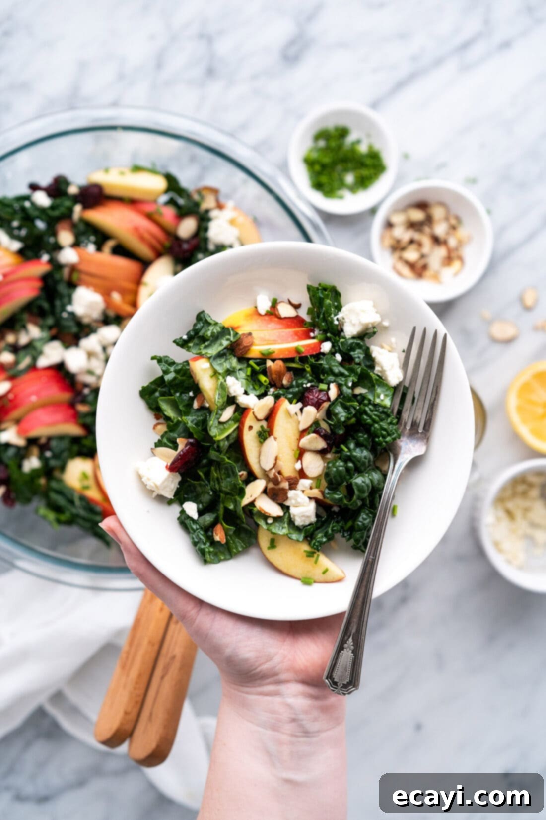 Signature Kale Salad 12 Singe serving of Kale Salad in a bowl being held over the batch of Kale Salad