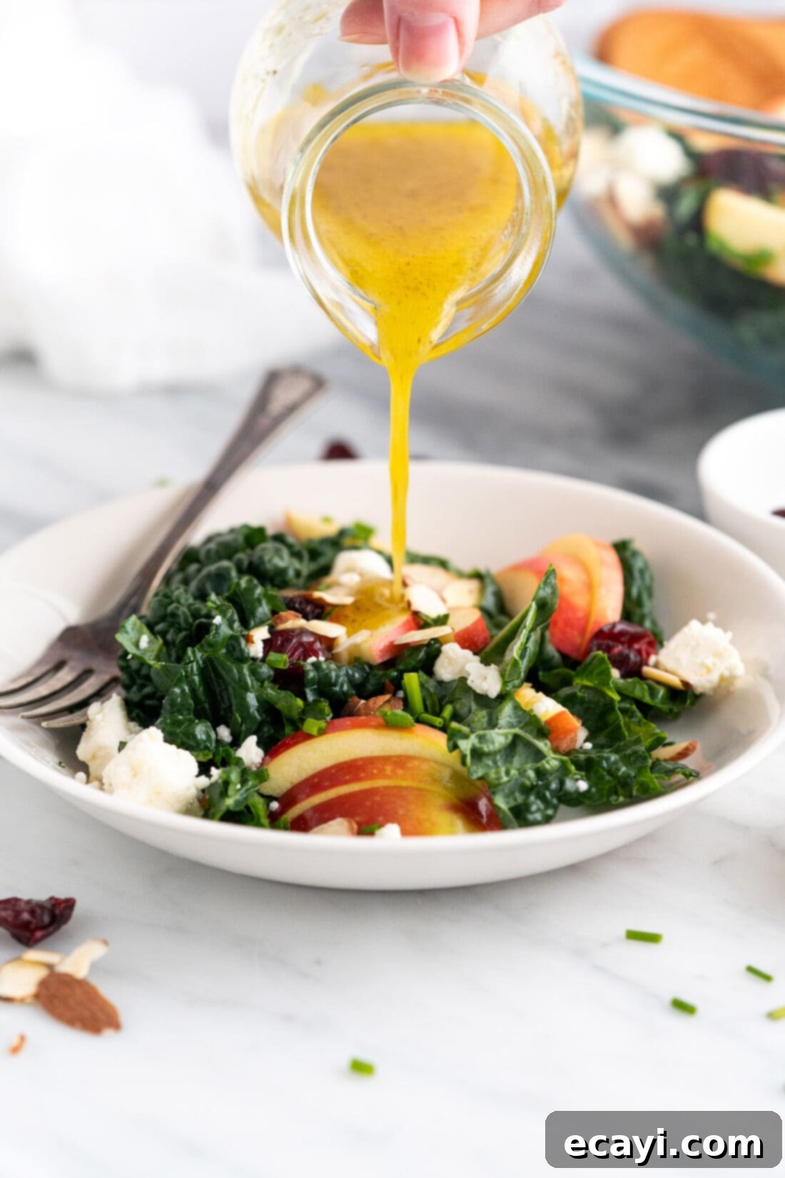 Signature Kale Salad 3 Fresh lemon dressing being drizzled over a bowl of Kale Salad