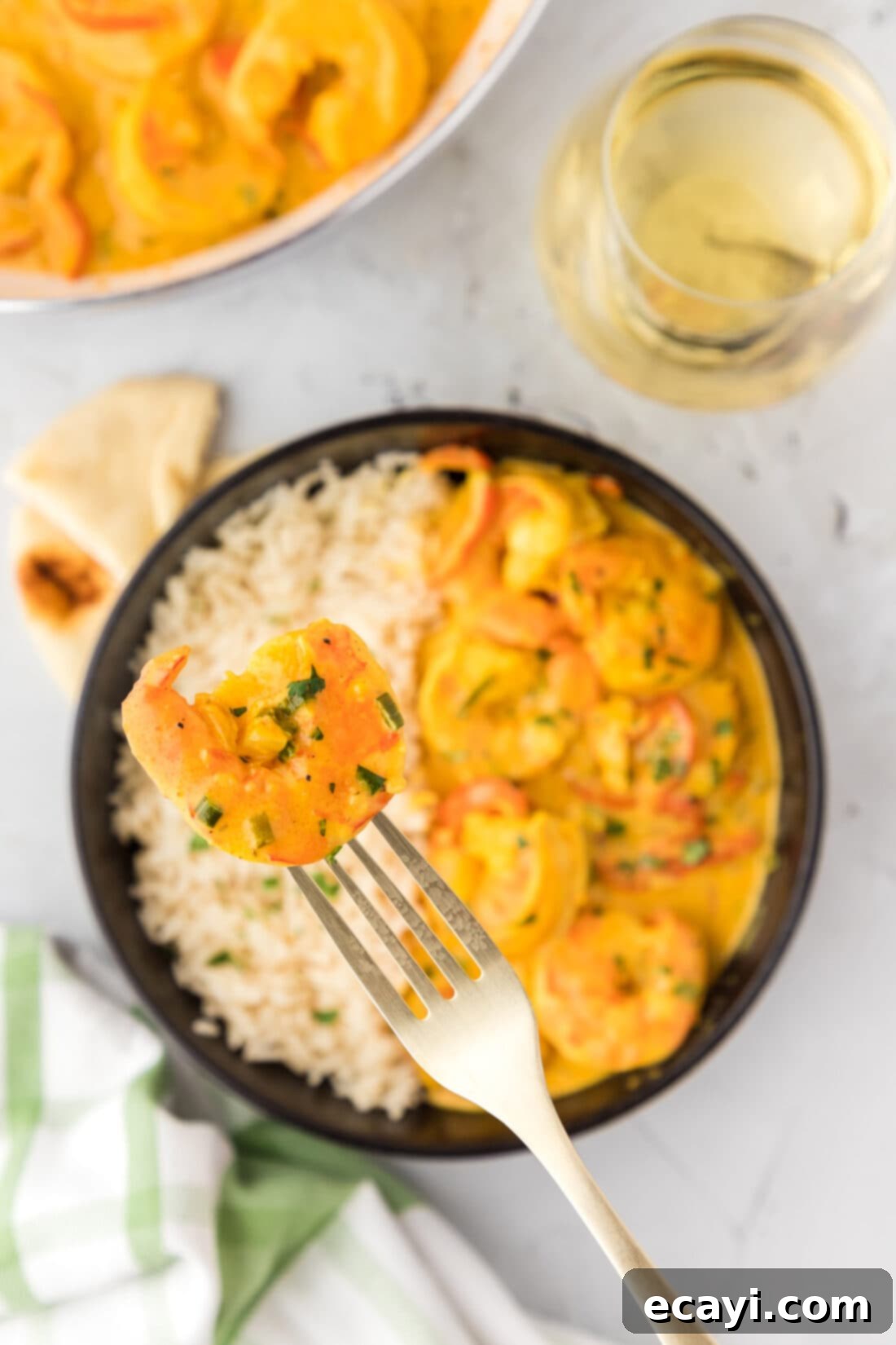 Mouthwatering Shrimp Curry 2 A fork holding a piece of shrimp and bell pepper, lifted above a bowl of creamy shrimp curry served with rice. The dish showcases juicy shrimp, vibrant red bell peppers, and a rich, golden sauce.