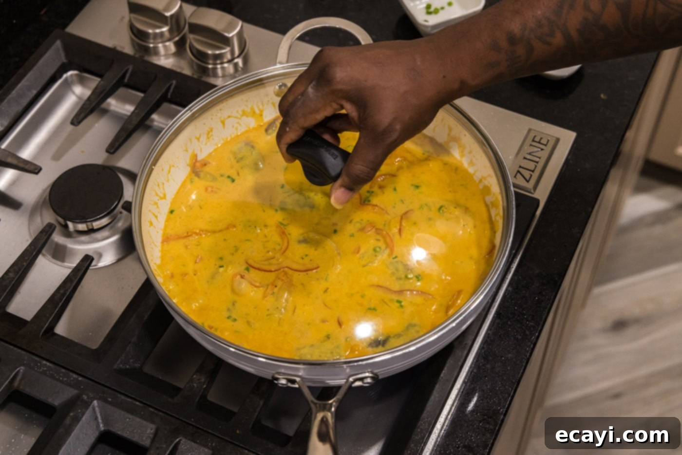 Mouthwatering Shrimp Curry 11 A lid being placed onto the skillet of shrimp curry, allowing it to simmer gently on the stovetop and cook the shrimp thoroughly.