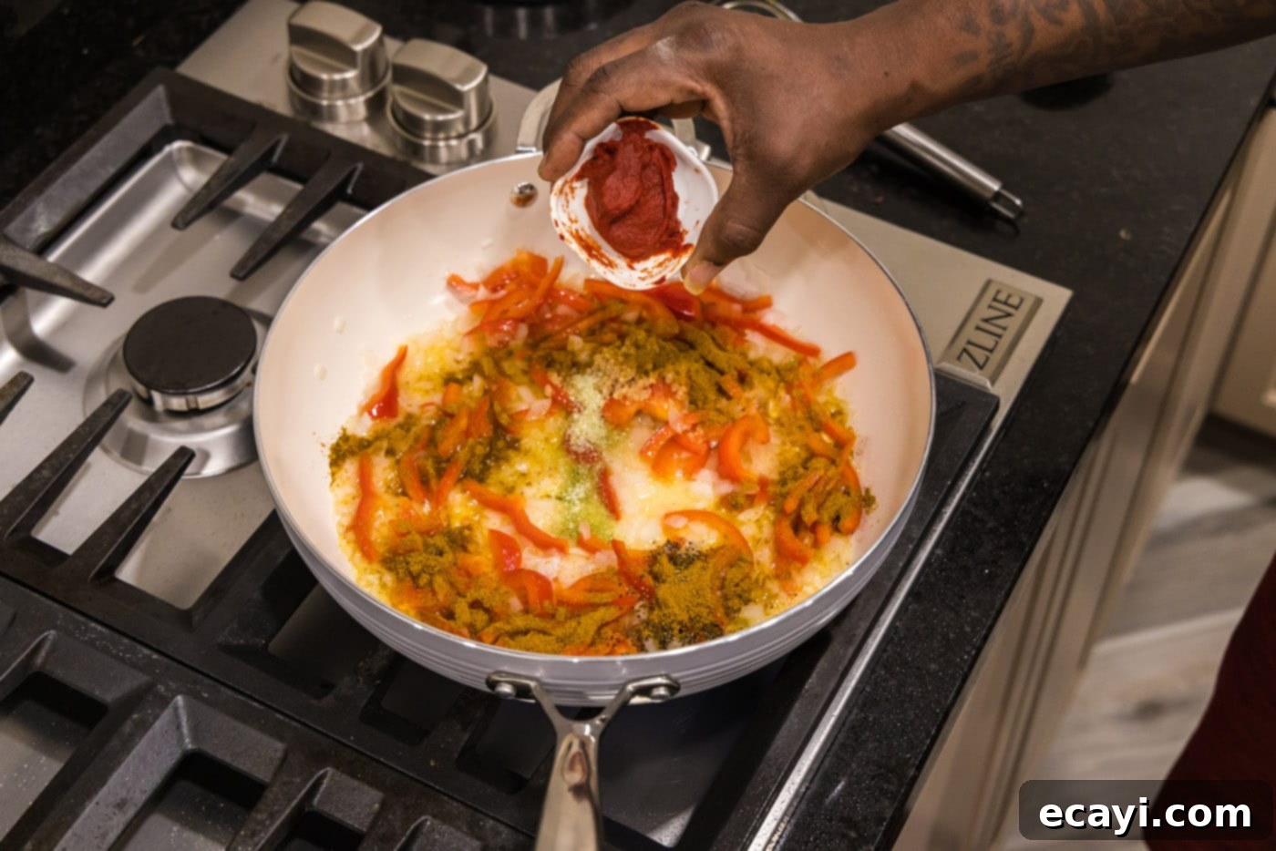 Mouthwatering Shrimp Curry 6 Minced garlic, black pepper, garlic salt, curry powder, and tomato paste being stirred into the sautéed onions and bell peppers in the skillet, creating an aromatic base.