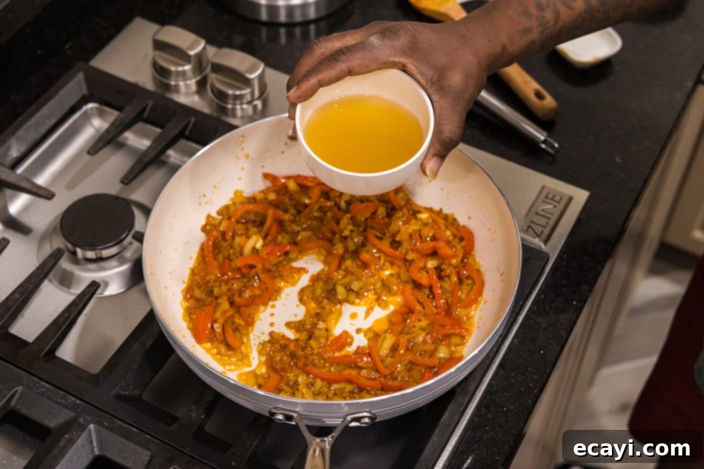 Mouthwatering Shrimp Curry 7 Pouring chicken stock into the skillet, blending it with the aromatic spices and vegetables to form the flavorful base of the curry sauce.