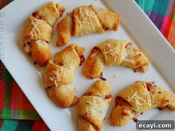 Cheesy Pizza Crescents 2 An overhead photo of golden-brown pizza crescent roll ups on a white platter, ready to be served as delicious snacks or appetizers.