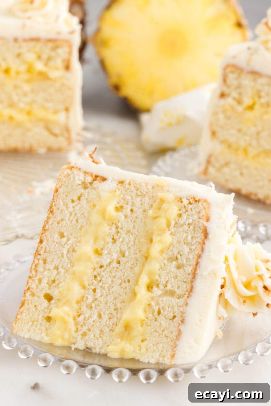 Pineapple Coconut Paradise 3 Slice of Pineapple Coconut Cake on a plate, showing the layers of cake, curd, and frosting