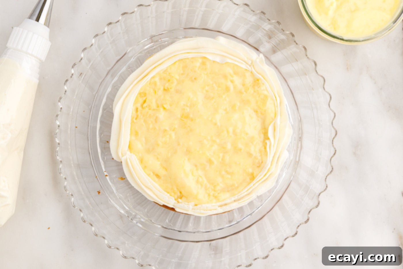 Pineapple Coconut Paradise 21 piping a ring of frosting on the first cake layer to create a dam for filling