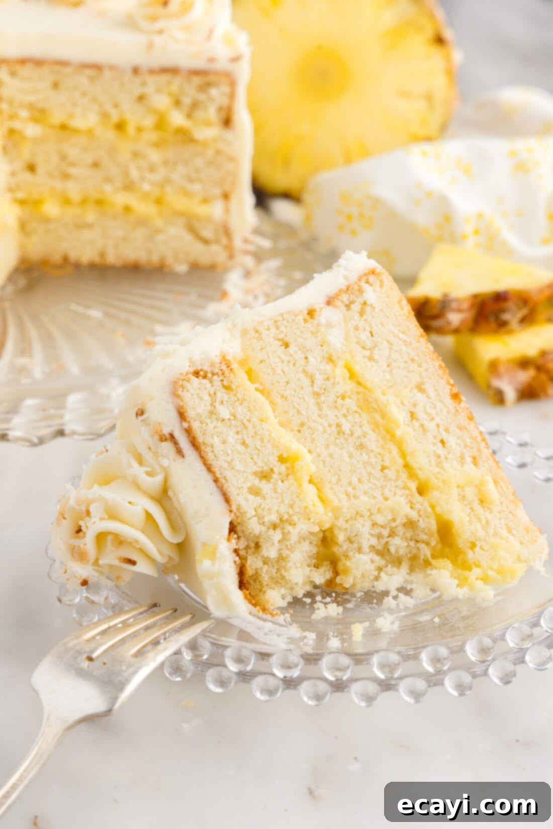 Pineapple Coconut Paradise 25 Partially eaten slice of Pineapple Coconut Cake on a plate with a fork, showing the moist interior