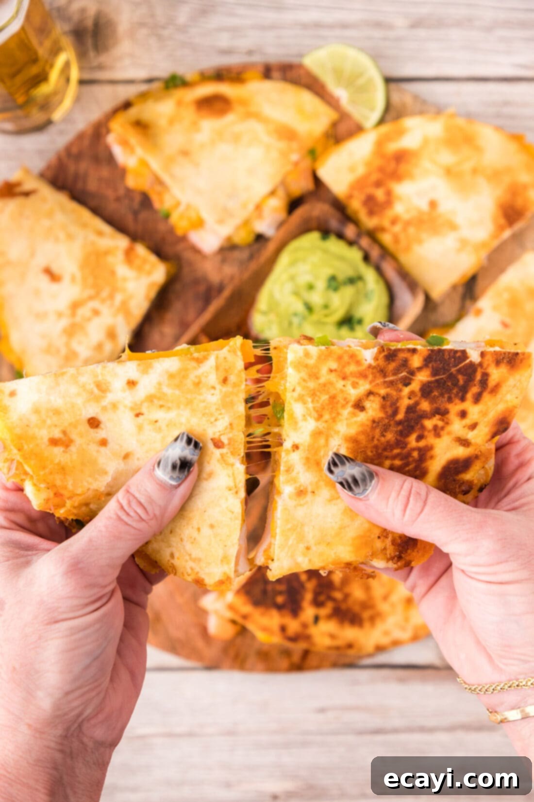 Zesty Shrimp Quesadilla 2 Hands pulling two Shrimp Quesadilla triangles apart, showcasing the gooey cheese and flavorful filling.