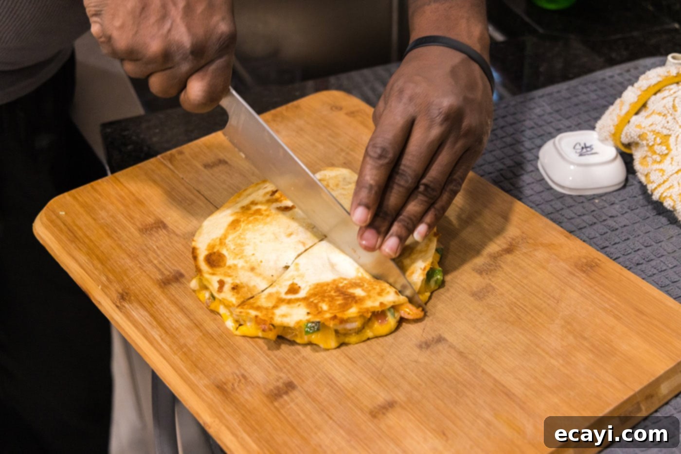 Zesty Shrimp Quesadilla 15 A knife slicing a freshly cooked shrimp quesadilla into wedges on a cutting board.
