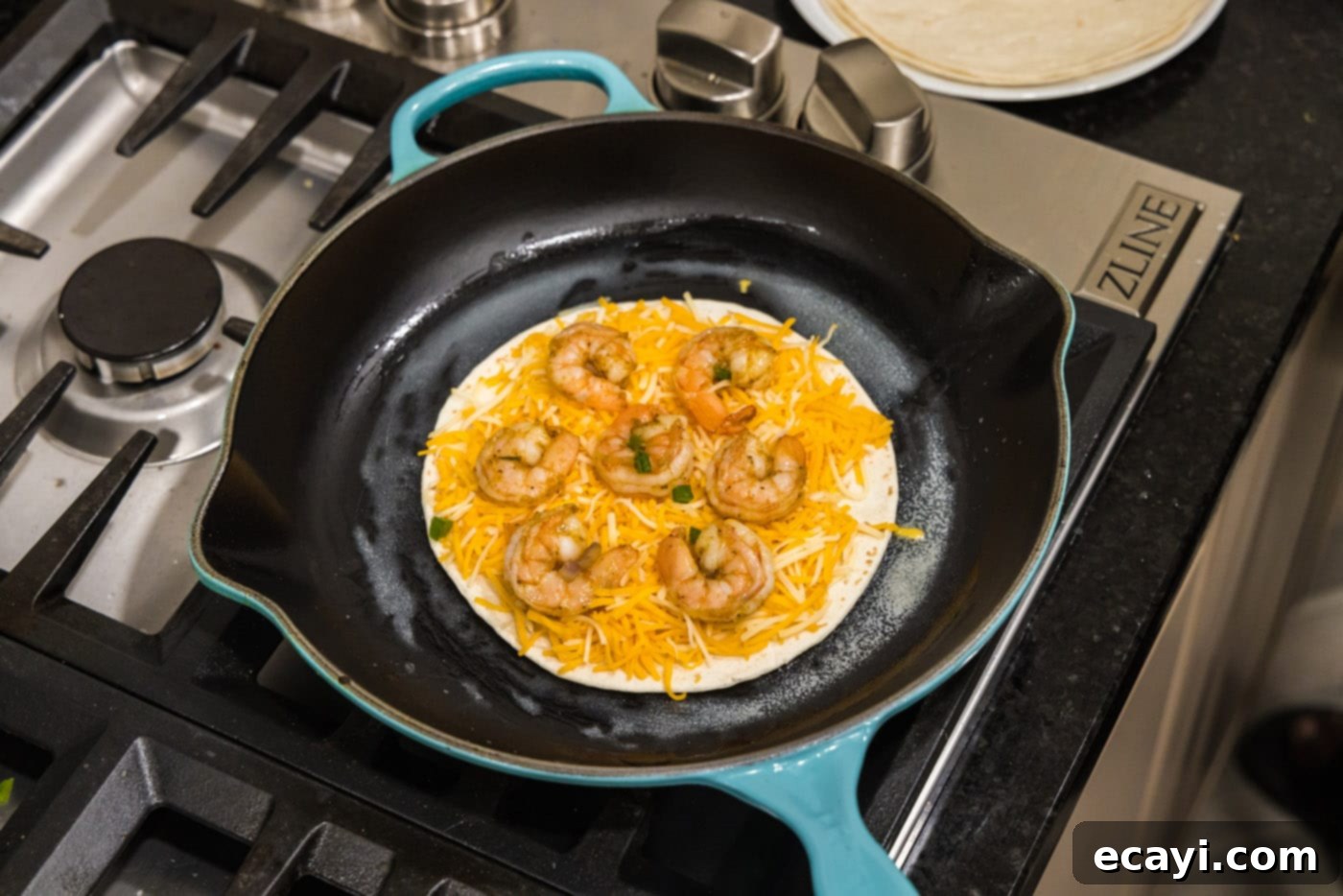 Zesty Shrimp Quesadilla 9 Adding seasoned shrimp to a tortilla already topped with shredded cheese in a hot skillet.