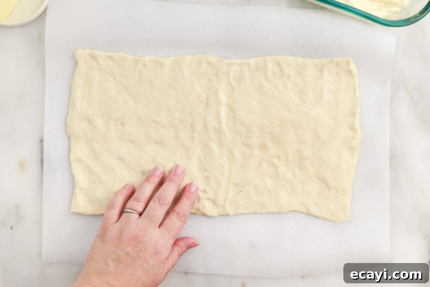 Cinnamon Swirl Sopapilla Cheesecake 11 A perfectly smoothed sheet of crescent dough resting on parchment paper, shaped and ready to be placed over the cheesecake filling.