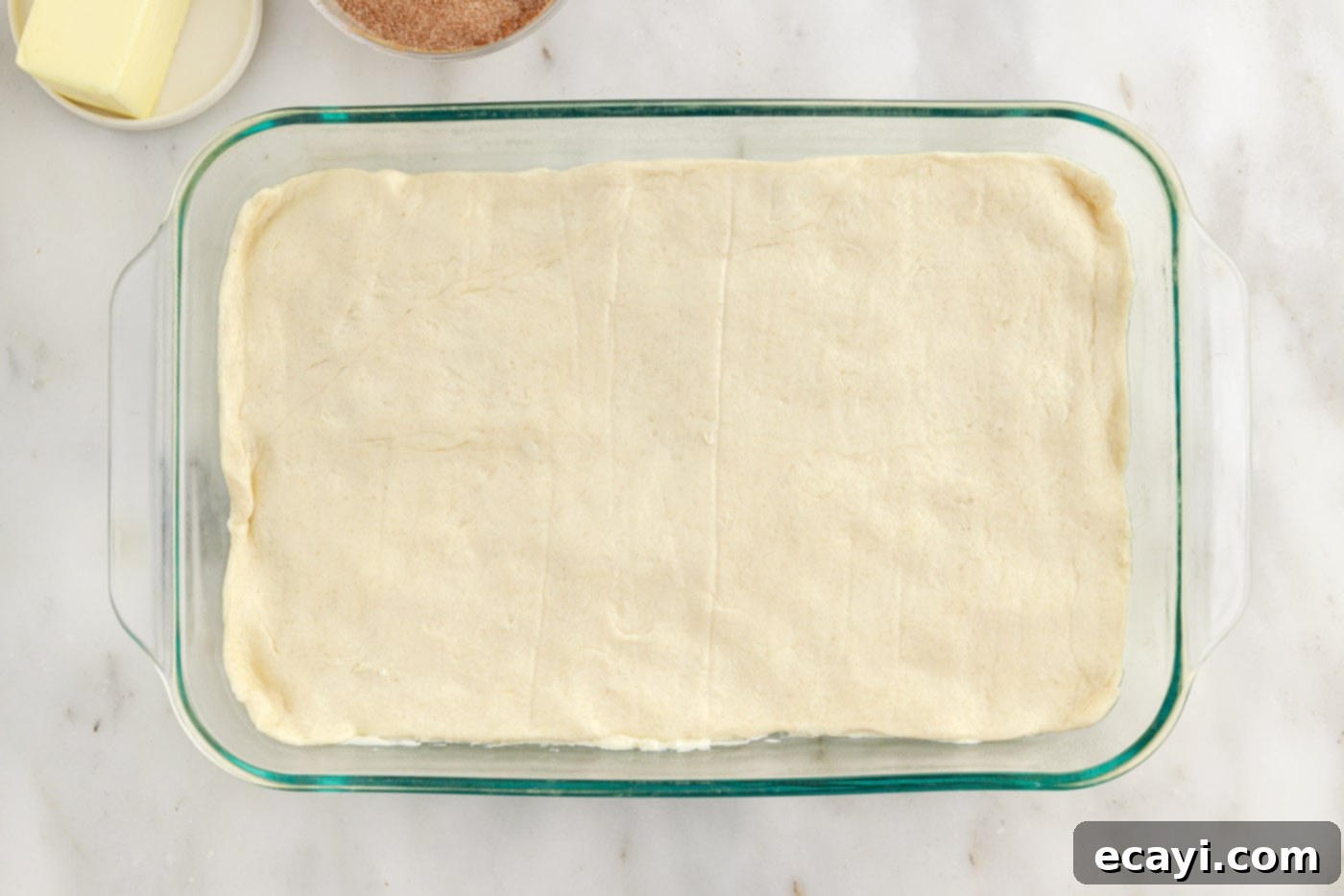Cinnamon Swirl Sopapilla Cheesecake 13 The top layer of crescent dough securely in place, covering the cheesecake filling, with all edges neatly tucked into the baking dish.