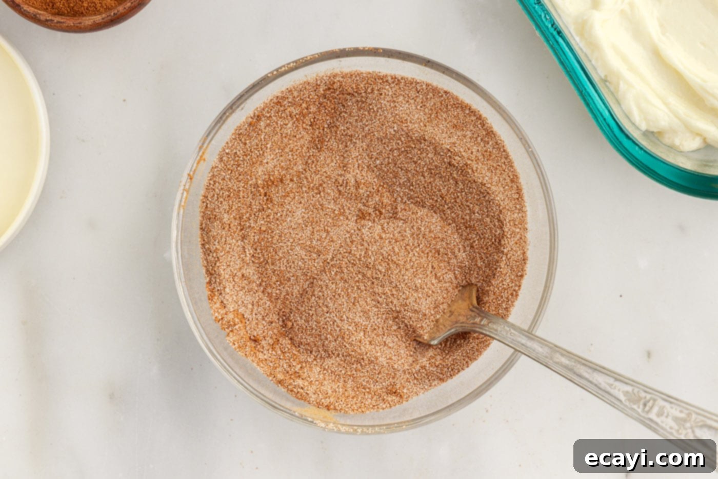 Cinnamon Swirl Sopapilla Cheesecake 14 A small bowl containing a perfectly mixed blend of granulated sugar and ground cinnamon, ready to be sprinkled.