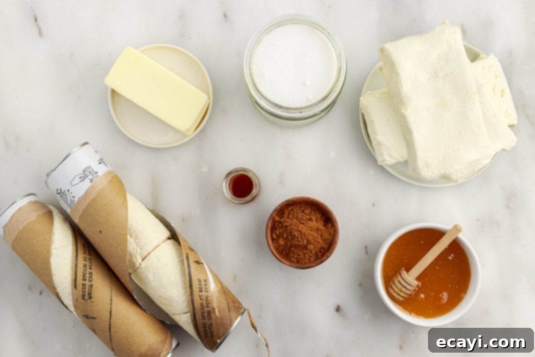 Cinnamon Swirl Sopapilla Cheesecake 4 All the necessary ingredients for Sopapilla Cheesecake bars neatly arranged on a kitchen counter, including crescent rolls, cream cheese, granulated sugar, vanilla extract, unsalted butter, and ground cinnamon.