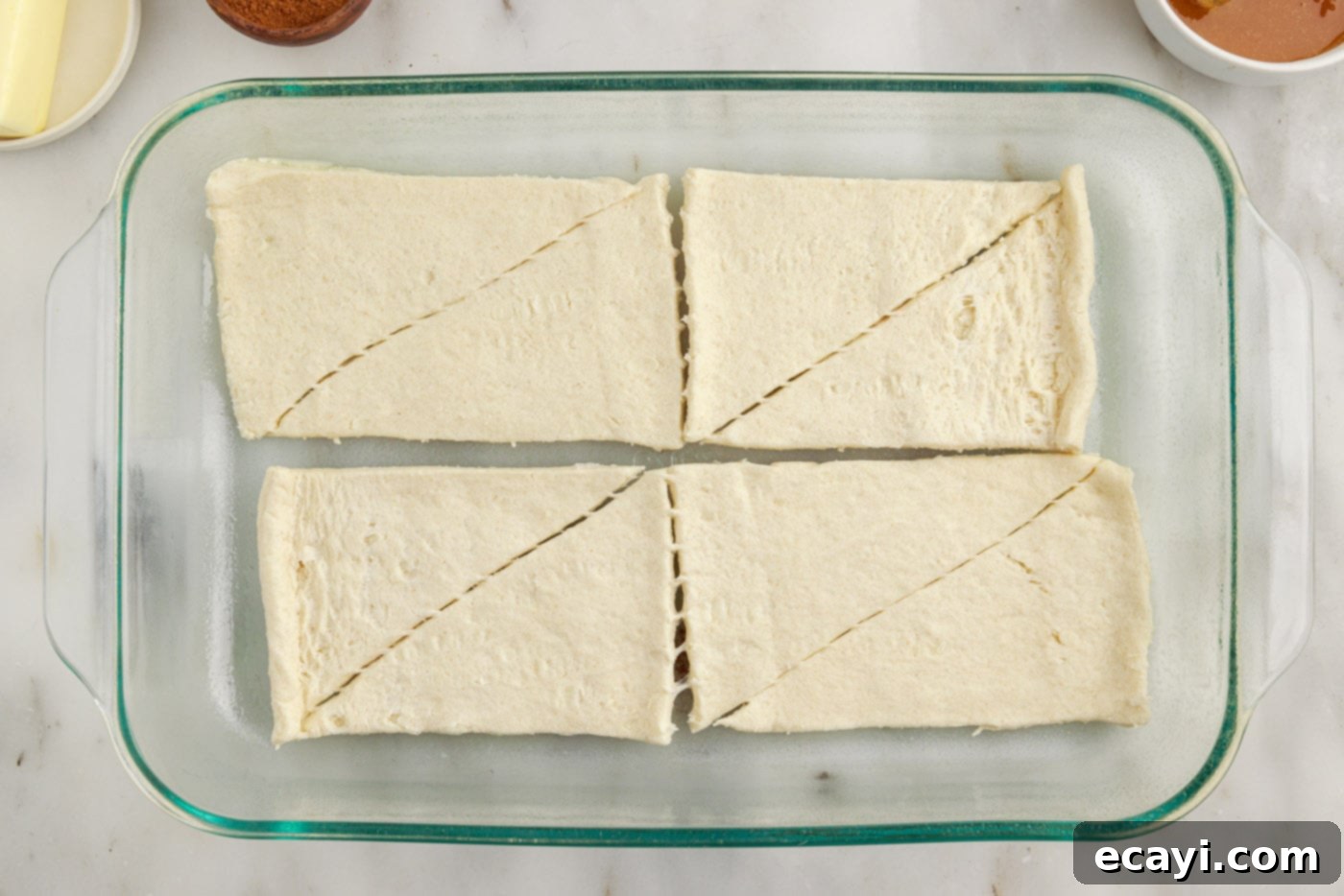 Cinnamon Swirl Sopapilla Cheesecake 5 Crescent roll dough carefully pressed into the bottom of a 9x13 inch baking dish, forming a seamless, golden-ready crust.