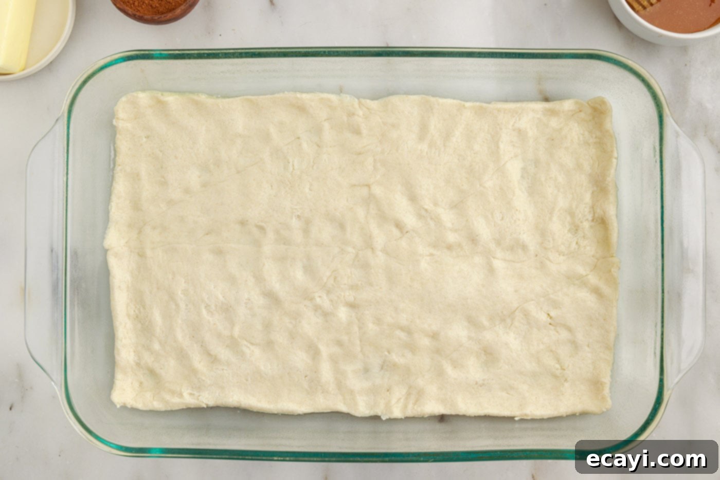 Cinnamon Swirl Sopapilla Cheesecake 6 A smooth, even layer of crescent dough fully covering the bottom of a baking dish, prepared to receive the creamy filling.