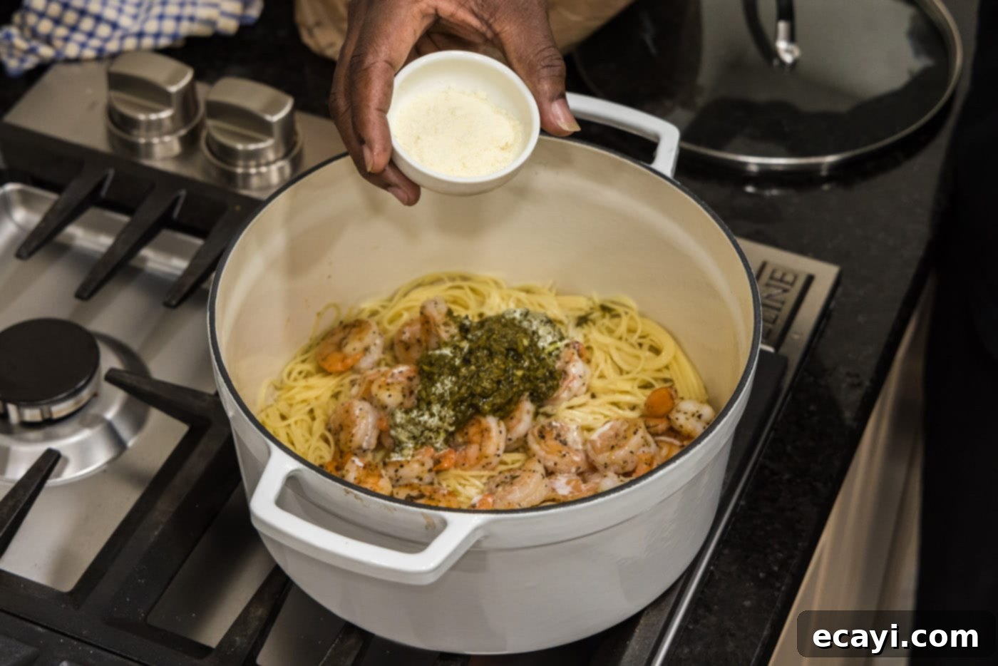 Vibrant Pesto Prawn Pasta 9 pouring parmesan into pot with shrimp pesto pasta