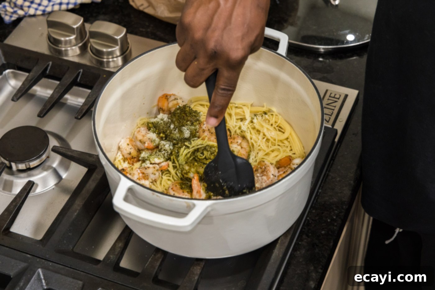 Vibrant Pesto Prawn Pasta 10 stirring shrimp pesto pasta with a rubber spatula
