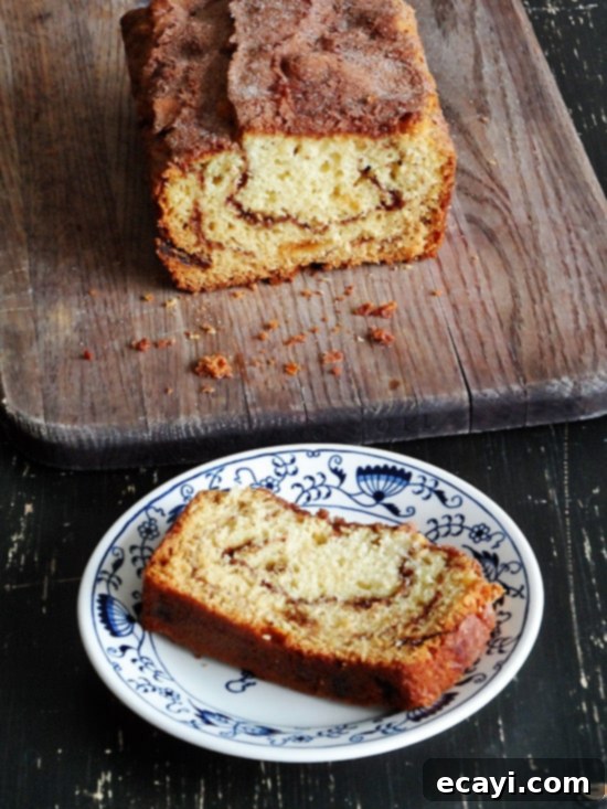 Ribboned Cinnamon Raisin Quick Loaf 2 An overhead photo of a loaf of cinnamon raisin swirl quick bread on a wooden cutting board and a slice on a plate.