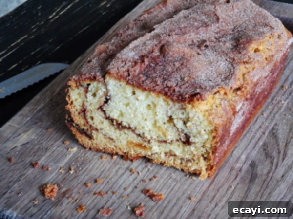 Ribboned Cinnamon Raisin Quick Loaf 6 A photo of a loaf of cinnamon raisin swirl quick bread on a wooden cutting board.